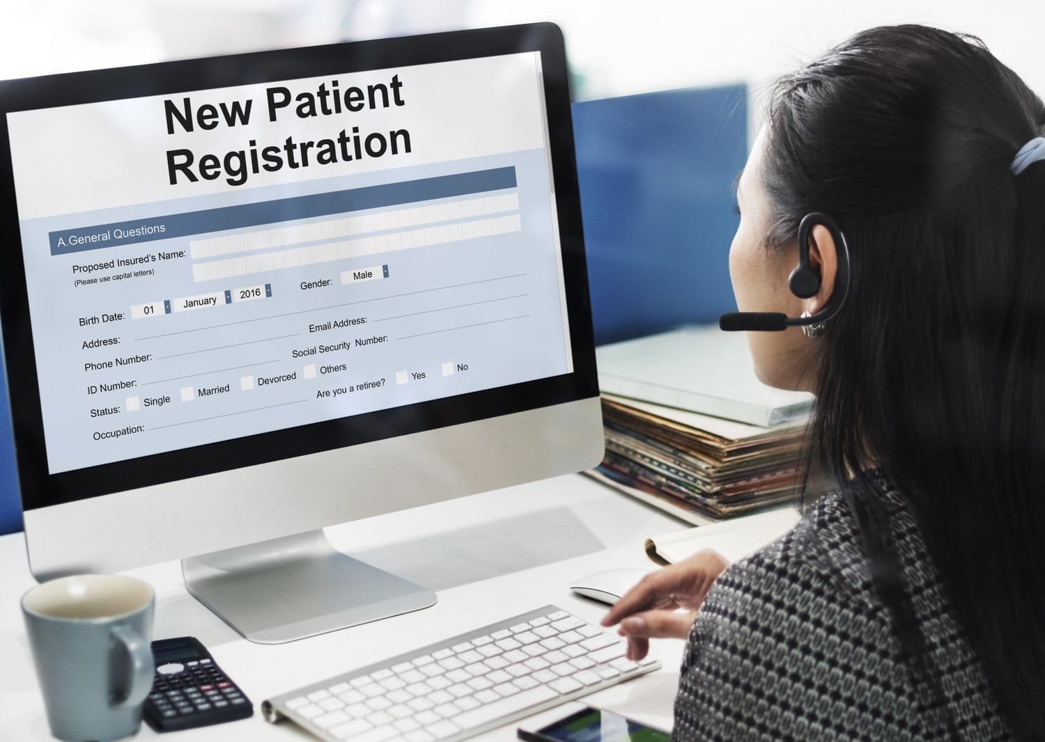a female adding information to a new patient registration form on computer