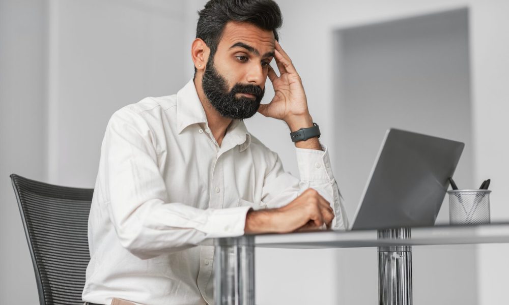 Man looking frustrated while working on his laptop