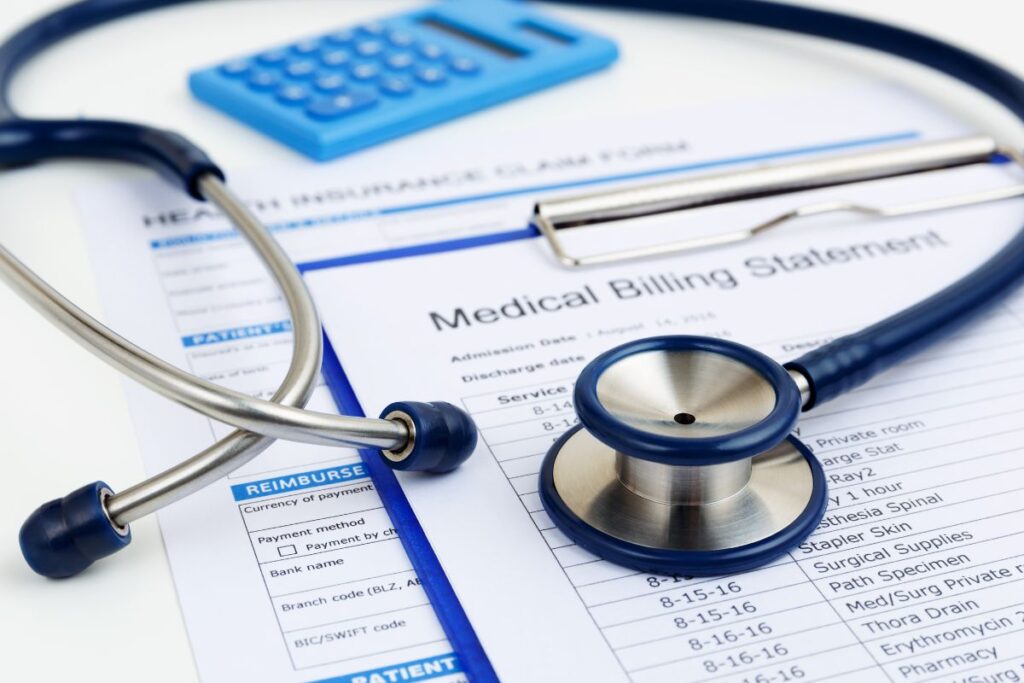 In-house billing vs outsourcing: Stethoscope and calculator resting on a medical billing statement and insurance forms
