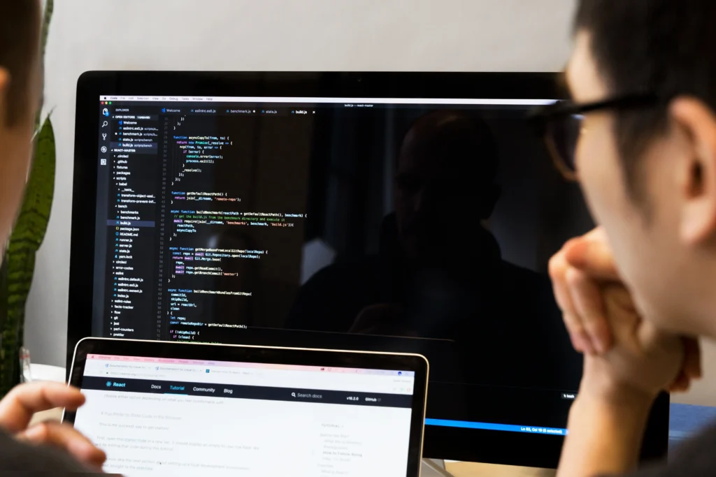 Two people reviewing code on a computer screen