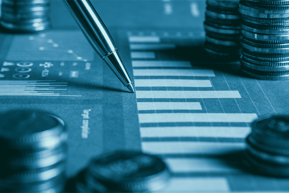 A pen pointing at a financial chart, with stacks of coins beside it, representing financial analysis and data.