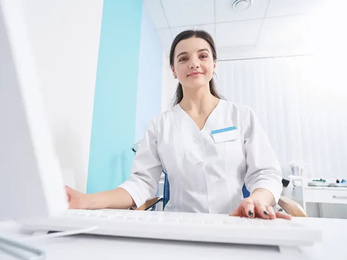 A medical professional working on a computer in an office setting.