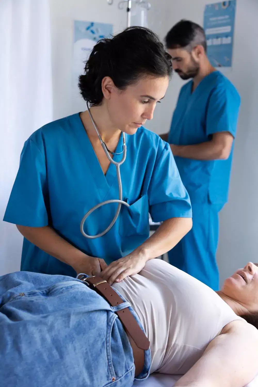 Nurse using a stethoscope to check a patient’s abdomen in a medical setting