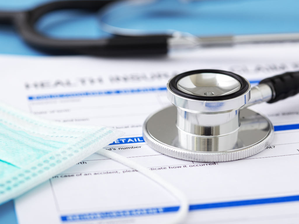 A stethoscope and health insurance form with a face mask, symbolizing medical services.