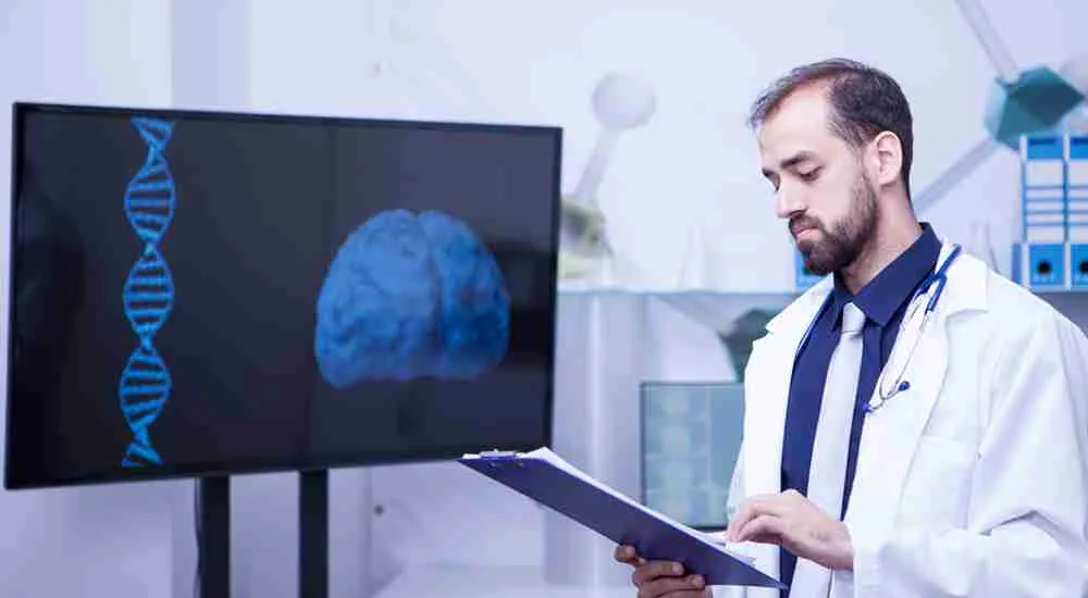 Doctor reviewing notes beside a screen showing DNA and brain visuals.