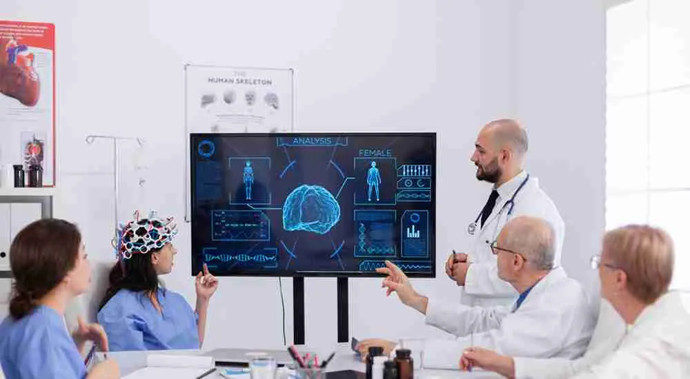 Medical team reviewing brain analysis on a digital screen together.