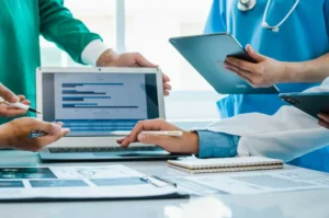 Medical professionals reviewing billing and analytics data on laptop and tablet.